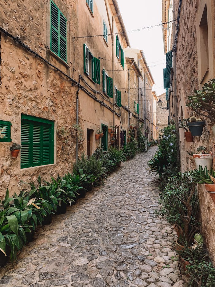 Picturesque narrow street with stone facades and green shutters in a Spanish old town, ideal for travel inspiration.