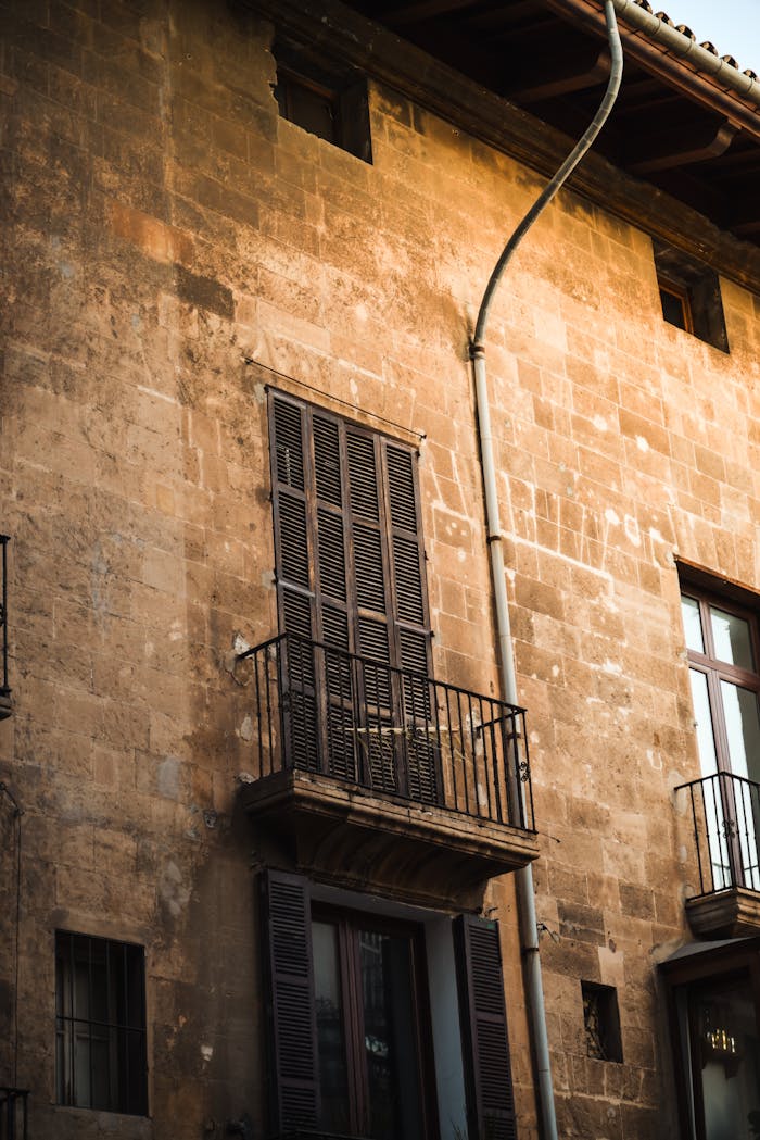 Aged stone building facade with balconies in Balearic Islands, Spain.